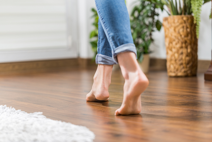 Floor heating. Young woman walking in the house on the warm floor. Gently walked the wooden panels.